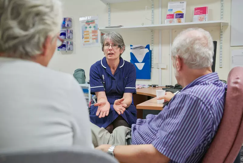 Nurse is sat talking to a man and a woman